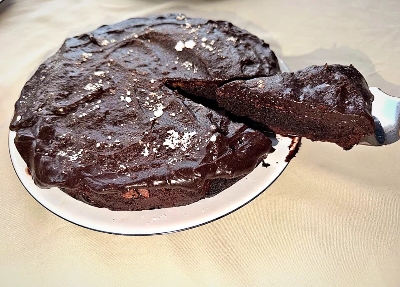 A glossy chocolate cake with a slice lifted